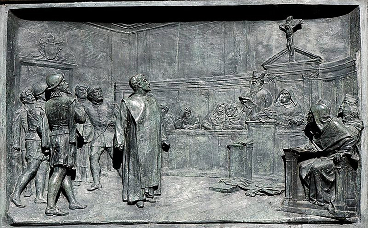 Giordano Bruno vor der Inquisitionskommision. Historisierendes Relief von Ettore Ferrari (1848-1929), Campo de' Fiori, Rome. Quelle: Jastrow / Wikimedia Commons